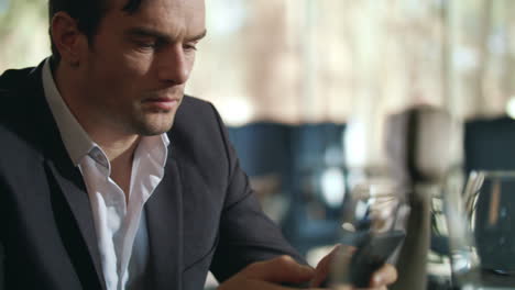 businessman looking mobile phone at restaurant. handsome man using cellphone