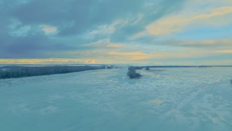 vista aérea, el helicóptero vuela sobre el río congelado, el río está en hielo. invierno hermoso paisaje, hielo se encuentra en el agua, alrededor del bosque, cielo azul. 4k, prores