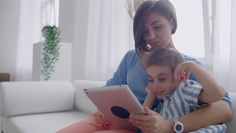 Mutter-Und-Sohn-Sitzen-Auf-Dem-Sofa-Und-Benutzen-Ein-Digitales-Tablet.-Glückliche-Mutter-Und-Kleiner-Junge-Benutzen-Ein-Tablet-Mit-Touchscreen-Und-Schauen-Gemeinsam-Ein-Video-An.-Lächelnde-Mutter-Und-Süßer-Junge-Spielen-Mit-Einem-Digitalen-Tablet.