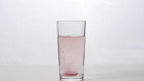 effervescent tablet falls into a glass of water on a white background