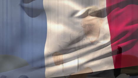 animation of flag of france over happy caucasian male architect working on blueprint