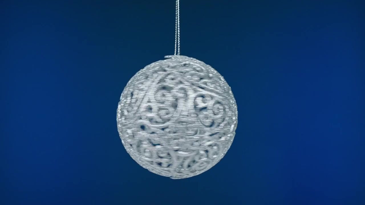 青い背景で回転する精巧な銀色のクリスマスオーナメント