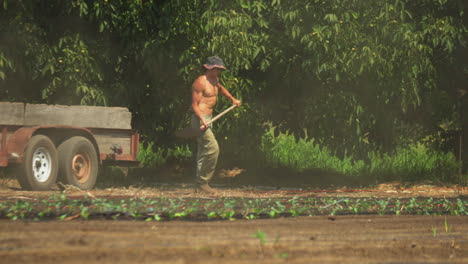 Joven-Granjero-Sin-Camisa-Al-Sol-Descargando-Tierra-Con-Una-Pala-De-Un-Camión-Al-Suelo