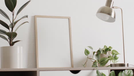marco de madera con espacio de copia en fondo blanco con plantas en el escritorio contra la pared blanca