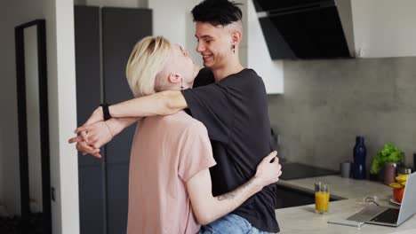 pareja de hombres homosexuales abrazándose y besándose en la cocina, un hombre sentado en un mostrador