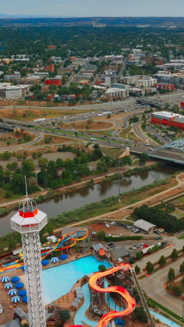 flying above elitch gardens amusement park and south platte river in denver, colorado, usa. panorama of big lively city with busy traffic. top view. vertical video