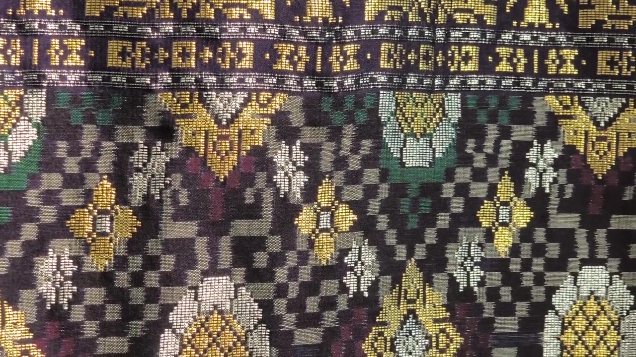 Detaljeret nærbillede af luksuriøst Songket-stof. Det indviklede guldbroderi skinner på den håndvævede overflade. Dette prestigefyldte malaysiske tekstil er forbeholdt de mest specielle lejligheder.