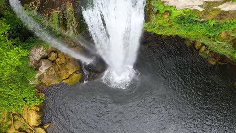 Aerial:-top-down-view-of-waterfall-overhang,-river-flowing-over-canyon-precipice