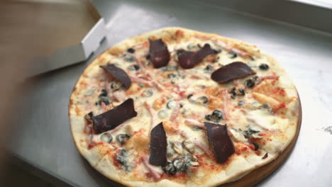 chef's hand adds spice to the pizza after cooking pizza in the kitchen of the restaurant. cooking food.