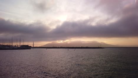 Gimbal-static-shot-of-fog-rolling-in-over-the-Golden-Gate-Bridge-at-magic-hour-in-San-Francisco,-California