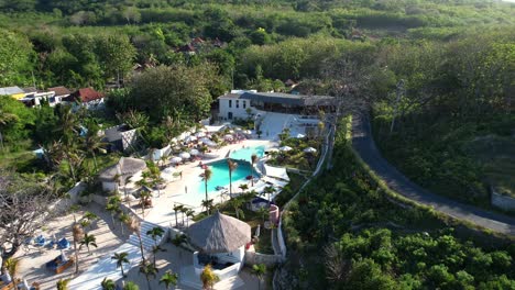 high angle aerial shot of cactus beach club with a luxury swimming pool and green trees view in nusa penida, bali, indonesia