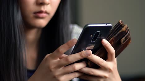 a young individual engaged with their smartphone and wallet, reflecting on modern communication and personal finance management in a digital age