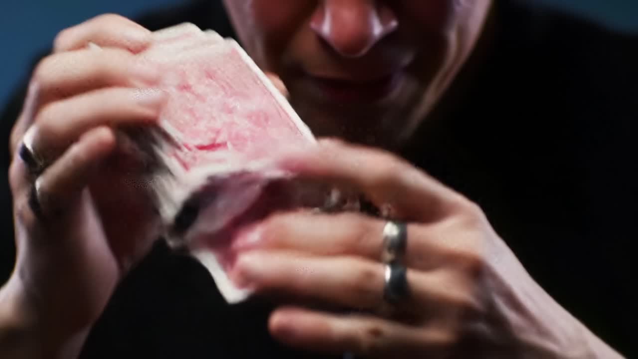 A Masterful Display of Card Manipulation: Close-Up Shots Capturing the Intense Focus and Skill of a Magician as He Engages in Card Tricks and Illusions