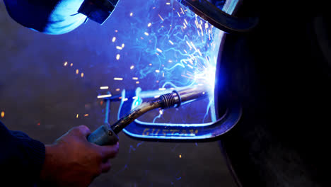 ingeniero masculino usando una antorcha de soldadura en el taller 4k