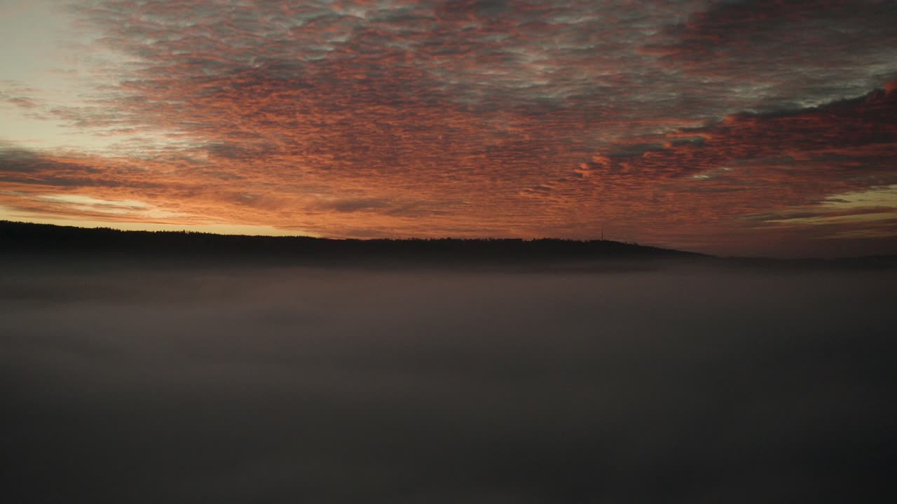 un espectáculo natural: puesta de sol roja y naranja sobre niebla