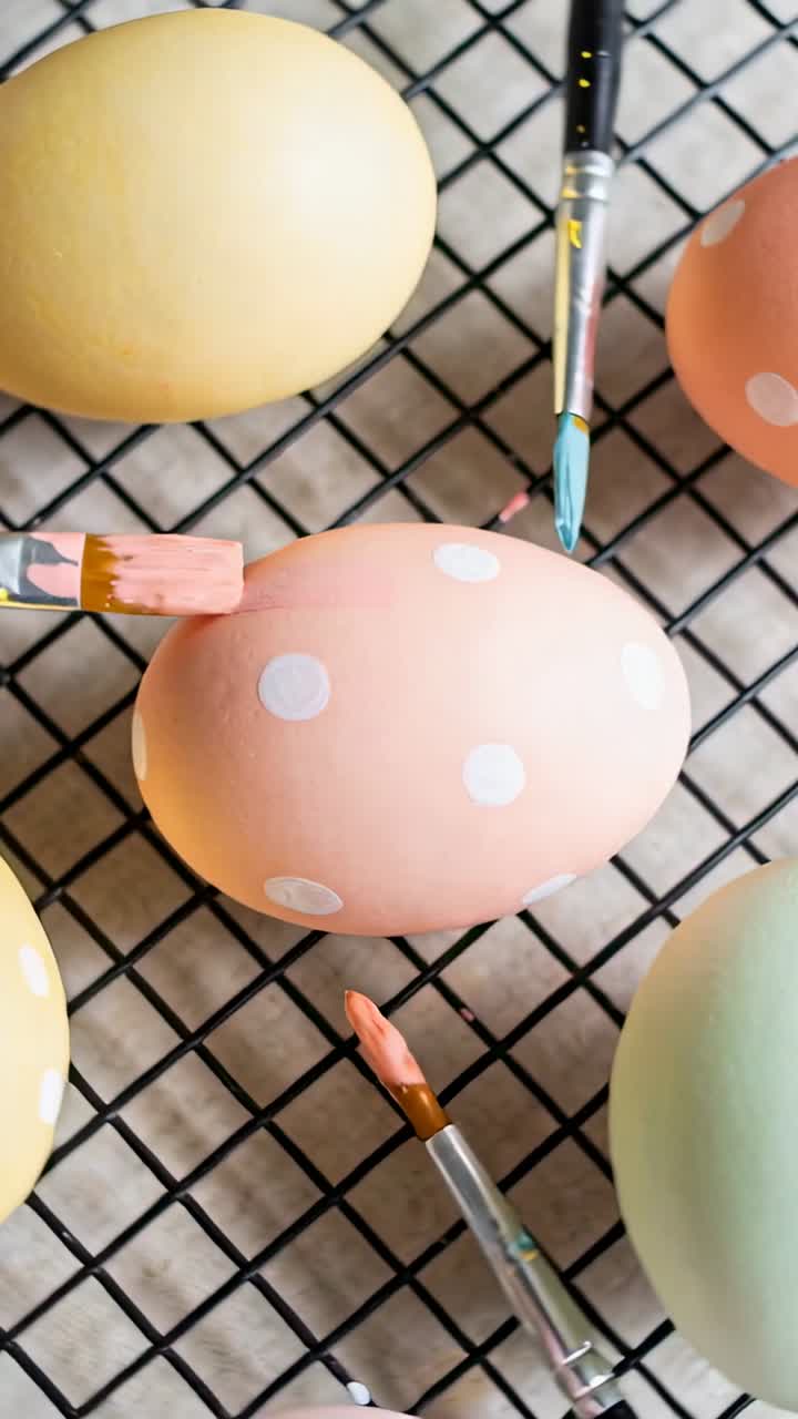 Vertical video: Stamping flat pink brush dotting pastel eggs for Easter on black wire rack