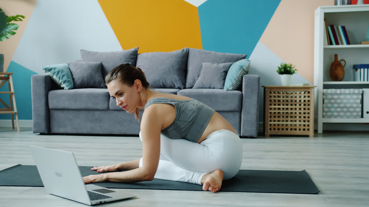mujer haciendo yoga en casa con laptop