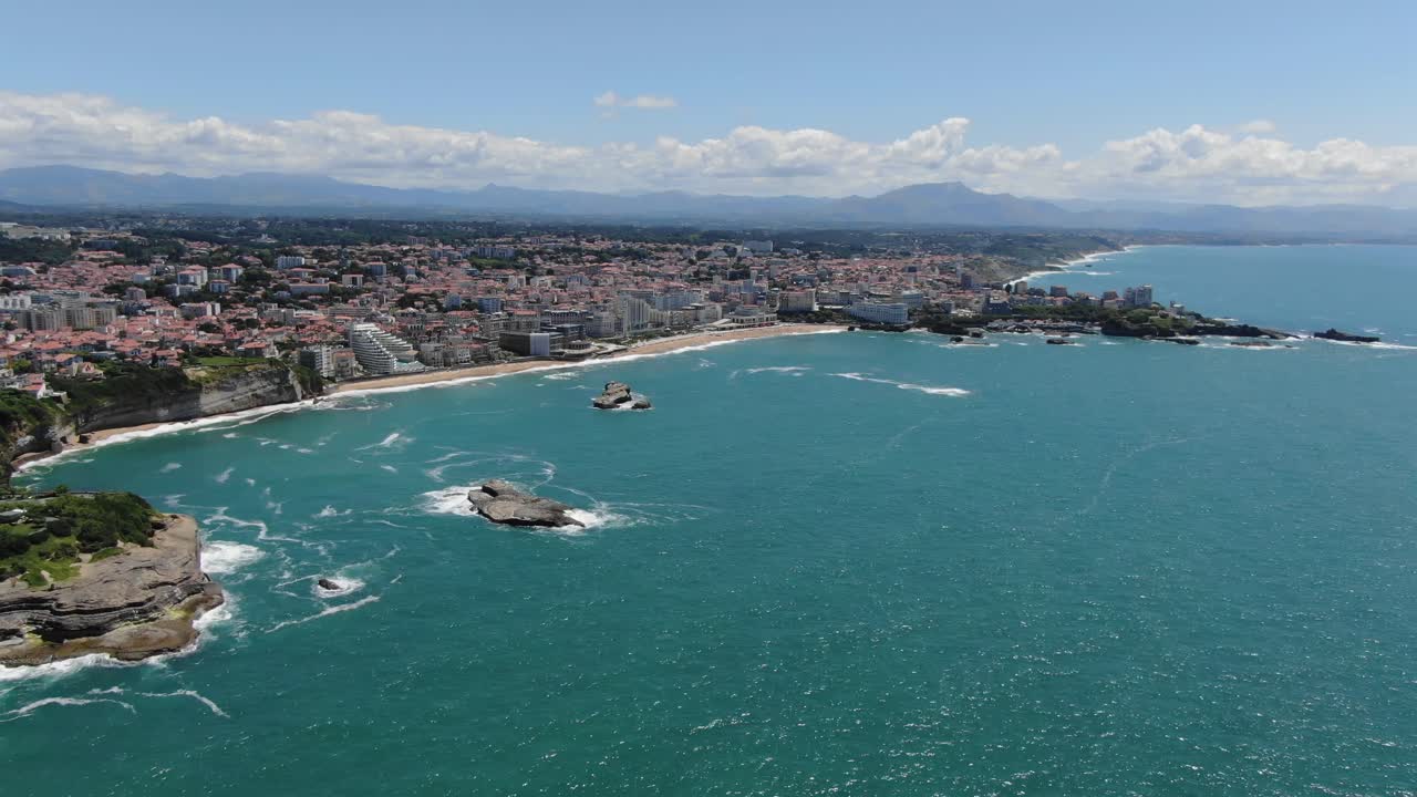 Biarritz cityscape and coastline, Grande Plage beach, Atlantic Ocean, Pyrenees mountains in background, France. Aerial forward, copy space