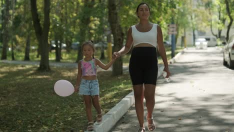 pregnant mother and daughter walking in park with balloon