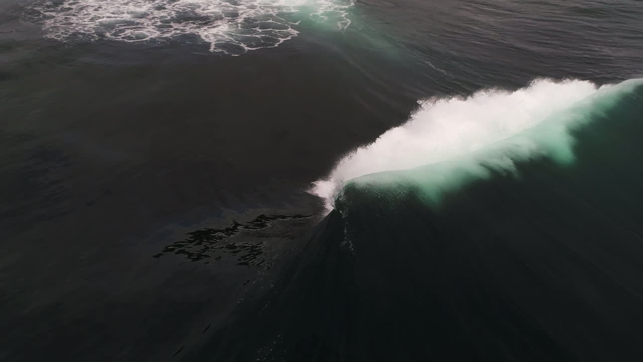 Massive wave rolls forward under moody sky with strong water texture