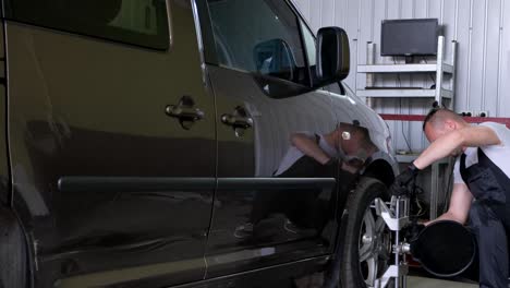 mechanic performing wheel alignment on a car