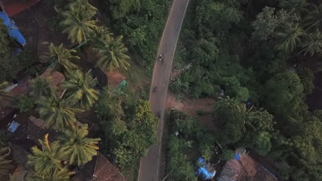 Aerial-tracks-motos-driving-on-thick-green-rural-jungle-road-in-India