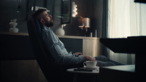 professional financial expert sitting in chair with closed eyes, resting after work and hard trading day. successful businessman in comfortable home office or investment bank office. dolly shot.