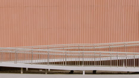 young american man in formal clothes going to work on bicycle and passing in front of a prefab metal building