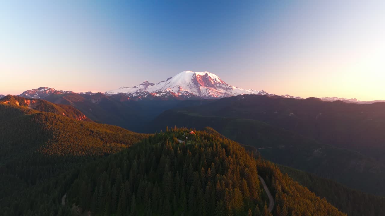 Drone shot pulling away from the Suntop fire lookout at sunset with Mount Rainier (Tahoma) in the background