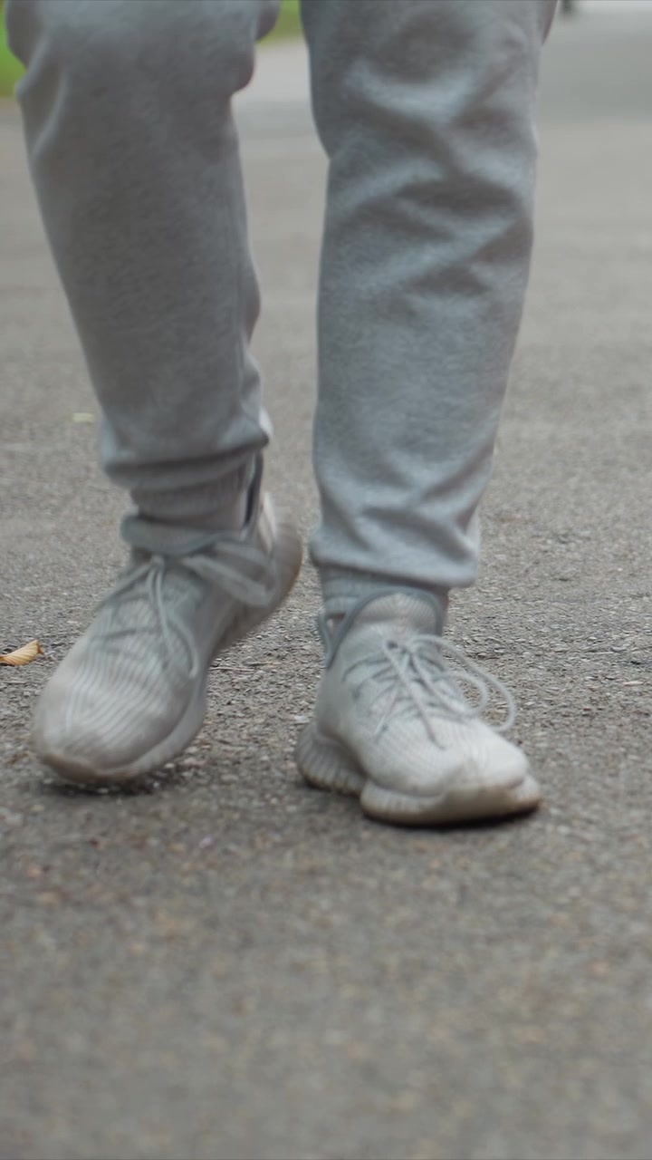 Individual wearing light gray pants moving forward. Alternating leg movements are highlighted by fixed camera. Background suggests natural surroundings with visible plant