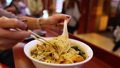 persona disfrutando de sopa de fideos con palillos