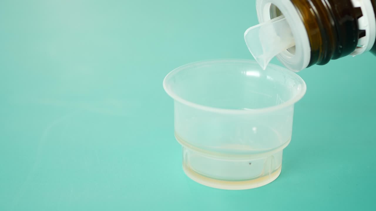 Pouring liquid medication into a measuring cup