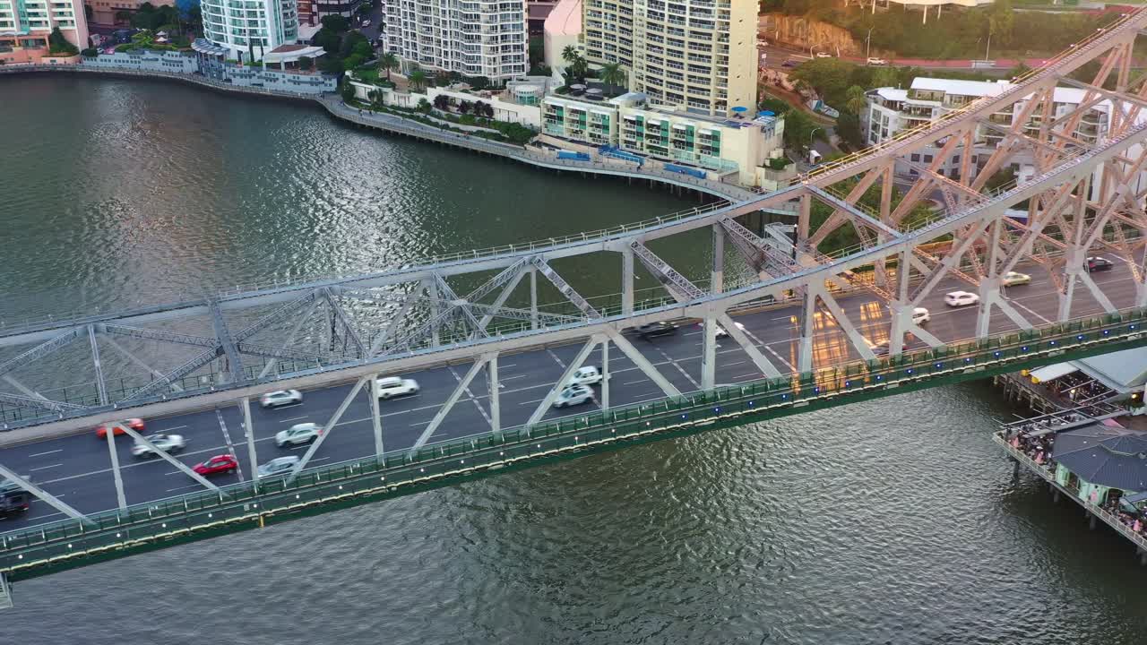 An aerial bird's-eye view flyover of the Brisbane River, capturing the hustle and bustle of commuting traffic on the iconic Story Bridge.