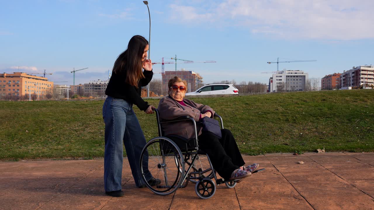 Granddaughter talking to her wheelchair-bound grandmother on a walk