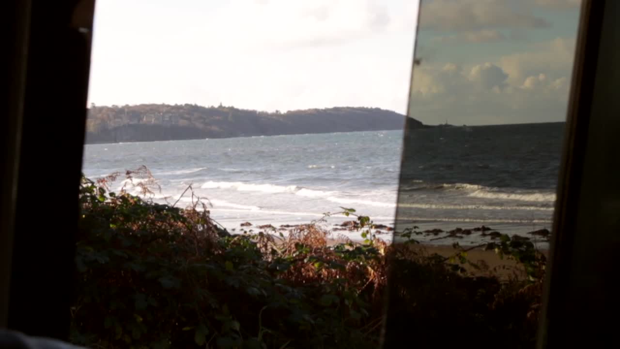 Waking up in van life vehicle on coast looking through window and enjoying the waves crashing and sun rising