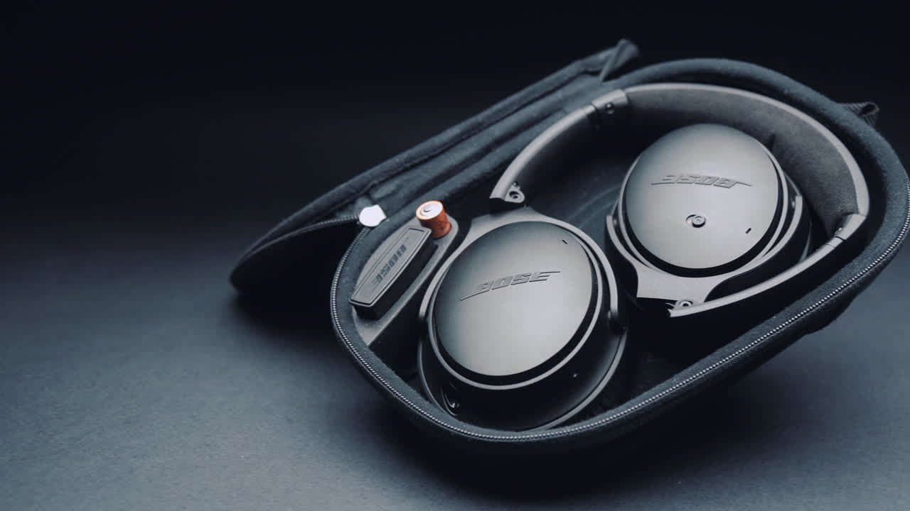 A product shot of black headphones on a black background, In a box. Camera movement  from right to left.
