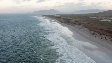 drone shot panning from berneray beach and the surrounding machair to the causeway joining berneray to north uist