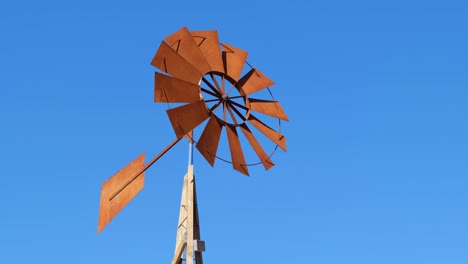 the wind pump fan blades are moving fast against the blue sky.