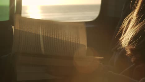 Mujer-Viajera-Leyendo-Un-Libro-En-Una-Camioneta-Al-Atardecer