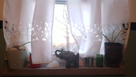 a window decorated in white curtains and candles at sunrise
