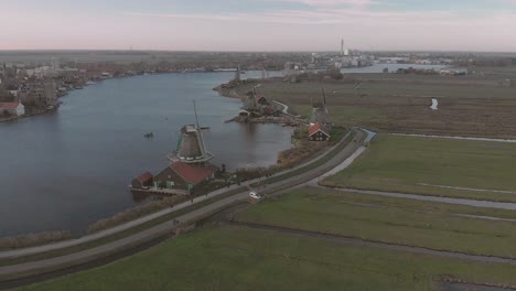 dutch landscape with meandering river with windmills with rotating wicks