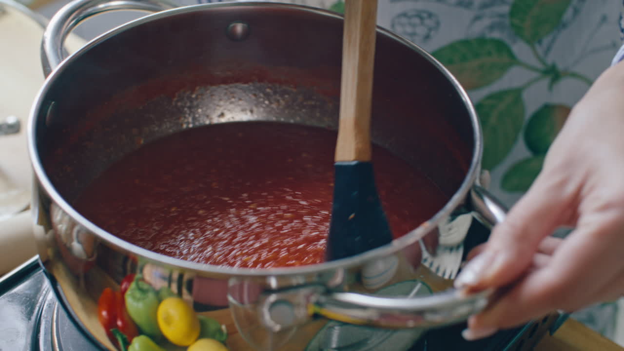 Hands of Woman Stirring Tomato Sauce in Pot during Cooking