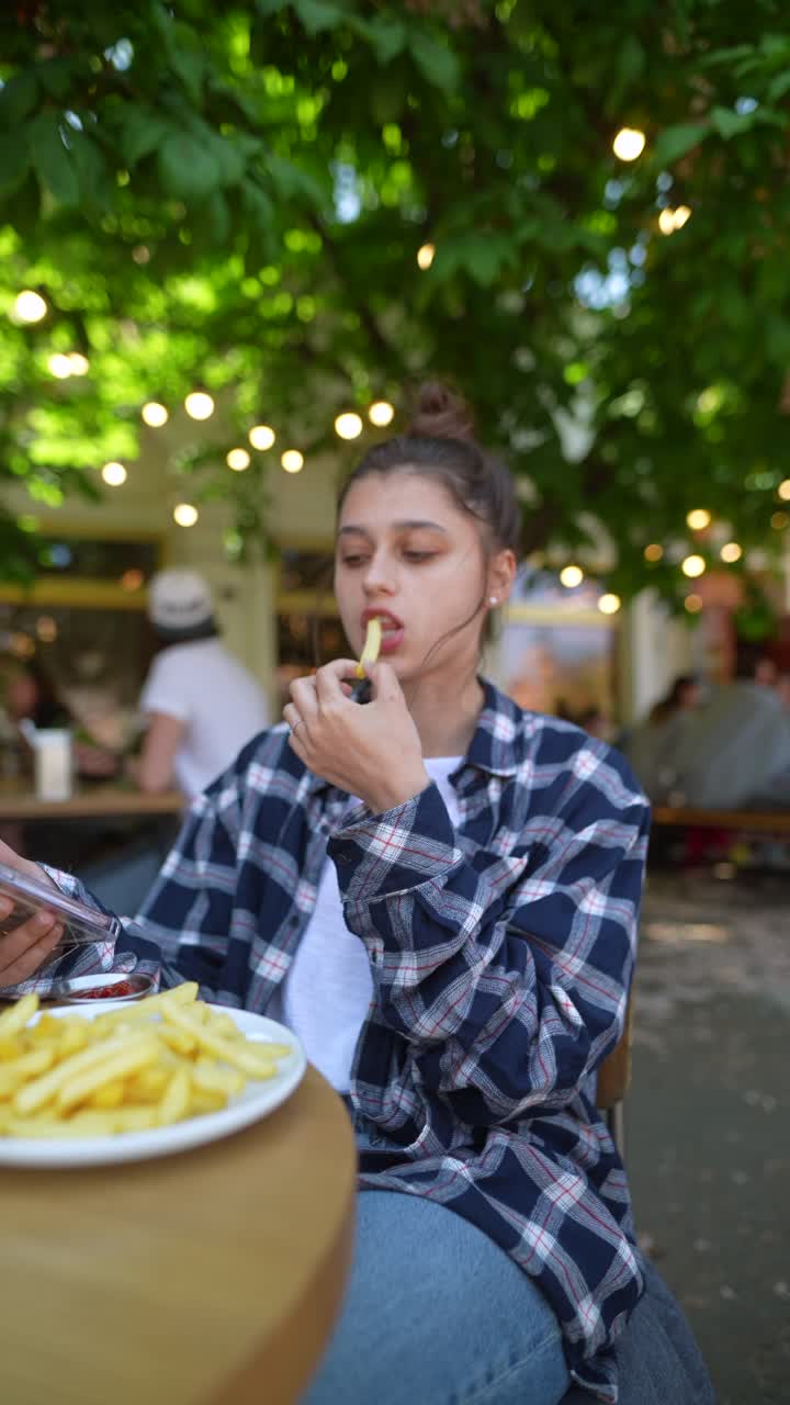 젊은 여성이 야외에서 감자김을 즐기고 있습니다.