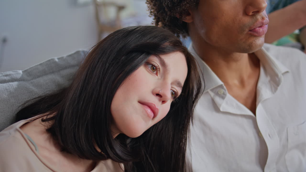 Brunette putting head boyfriend shoulder eating popcorn in front of tv closeup