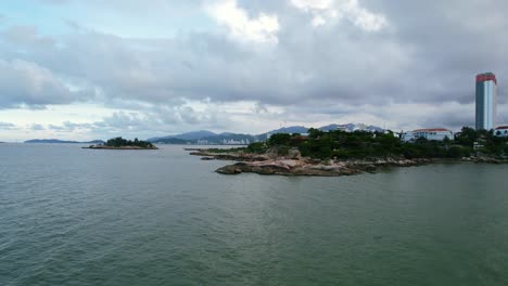 Niedrige-Höhe-Breite-Panoramische-Antenne-Der-Küste-Und-Des-Meeres-In-Nha-Trang-Vietnam-In-Der-Provinz-Khanh-Hoa-Während-Eines-Bewölkten-Sonnenuntergangs-Mit-Einer-Kleinen-Insel-In-Der-Ferne