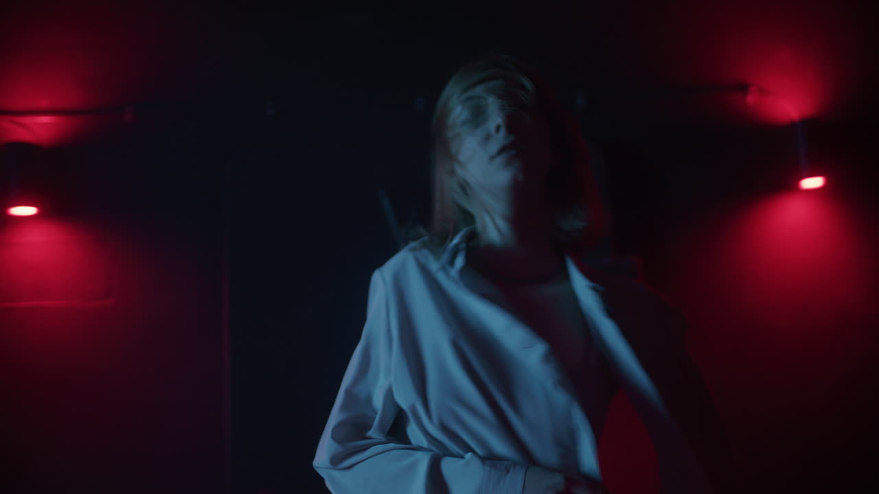 Woman dancing in a dark nightclub under red lights