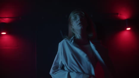 woman dancing in a dark nightclub under red lights