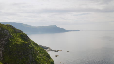 rugged mountain in the town of maloy, vagsoy island, norway overlooking calm lake on a foggy weather