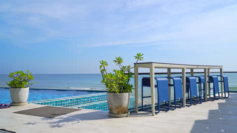 desk and bar stool near swimming pool with sea and sky background