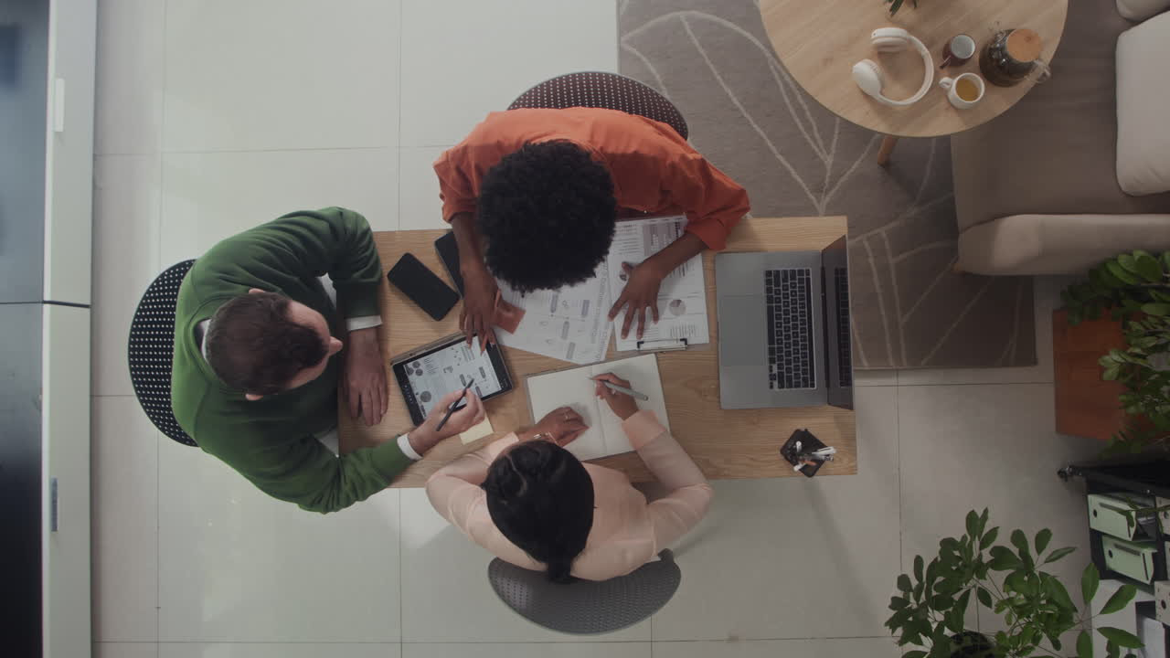 Three Businesspeople Discussing Partnership at Table with Documents